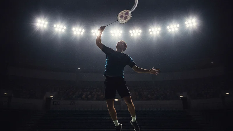 Badminton player mid-smash under bright arena lights — Malaysia Masters betting guide at Maxim88